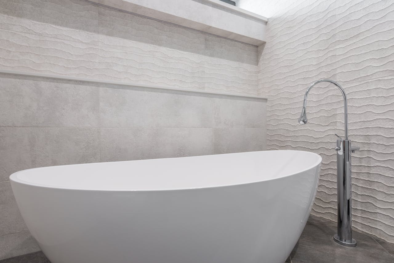 about-bg Modern minimalist style interior design of home bathroom with stone walls and oval white bathtub with chrome faucet